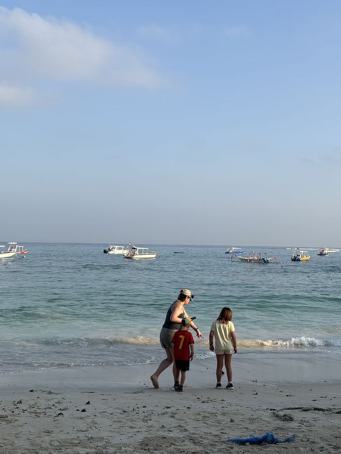 A mum and her kids paddling at the edge of the sea