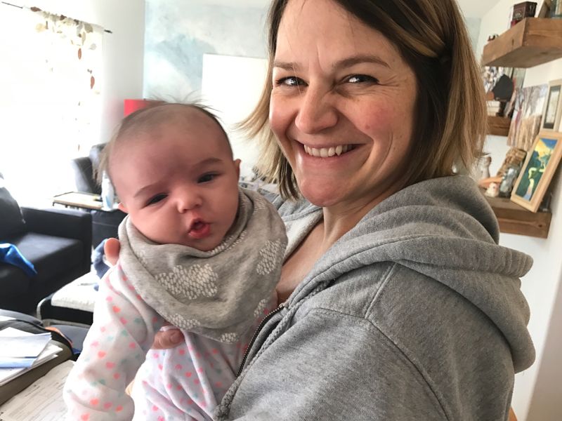 A smiling mum holding her baby at home
